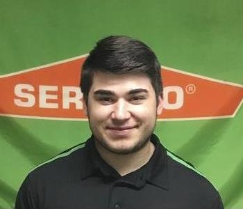 male employee in front of SERVPRO Logo'd banner smiling