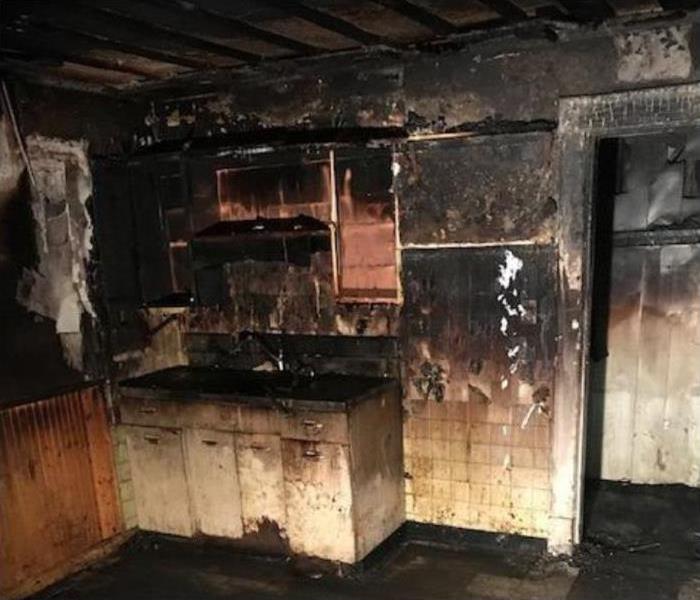 Heavily fire damaged kitchen; smoke, soot and charring on walls